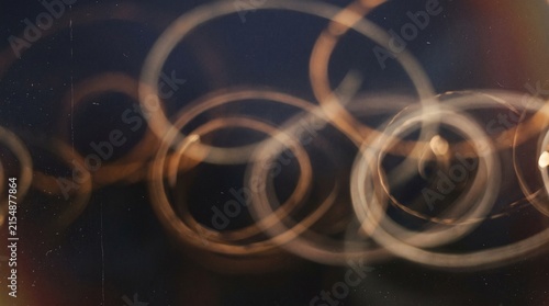 Abstract swirling light trails creating a mesmerizing pattern of golden rings against a dark background.