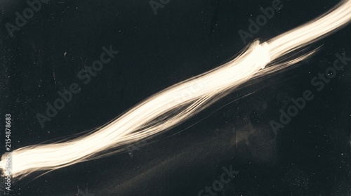 A luminous, elongated, and slightly blurred object resembling a bundle of glowing fibers against a dark background.