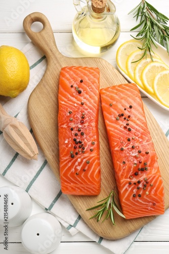 Pieces of raw salmon with spices on white wooden table, flat lay