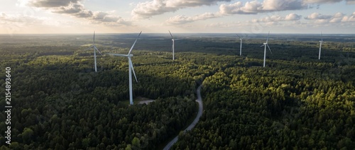Wind Farm Amidst Forest: An aerial view showcases a modern wind farm with towering turbines scattered across a dense, lush green forest, highlighting sustainable energy production.