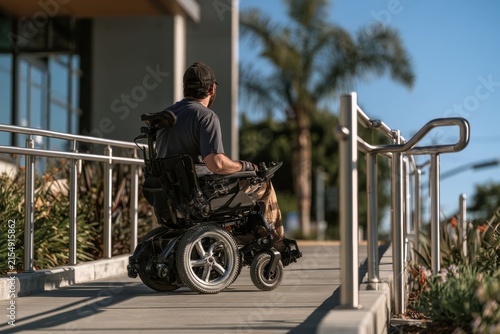 Man using power wheelchair on an outdoor accessibility ramp, showing independence and mobility
