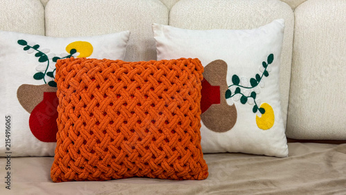 Cozy modern sofa styled with a chunky knitted orange cushion and decorative pillows, warm contemporary home interior with textured textiles.