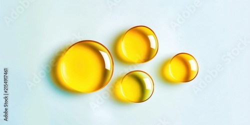 Golden oil droplets glistening on a clean, bright, light blue background