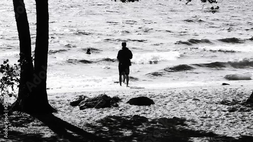 A single individual standing on a beach in black and white