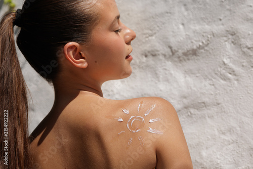 Fotografie Woman Applying Sunscreen with Sun Design on Shoulder