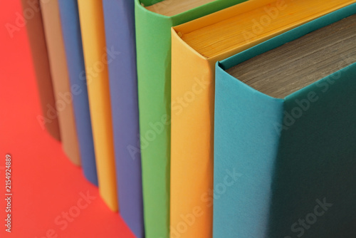Books with colorful paper covers are lined up against colorful paper backgrounds. School education featuring attractive, bright, and colorful books.