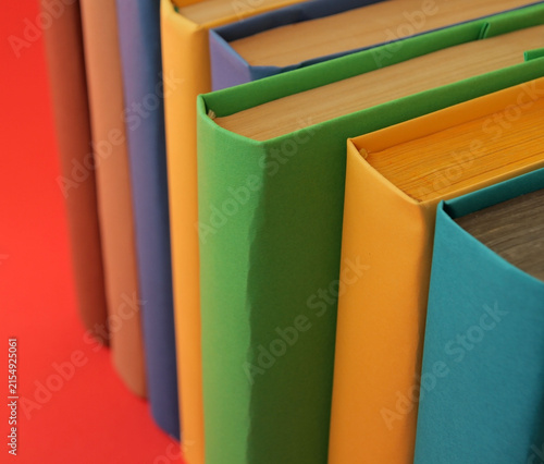 Books with colorful paper covers are lined up against colorful paper backgrounds. School education featuring attractive, bright, and colorful books.