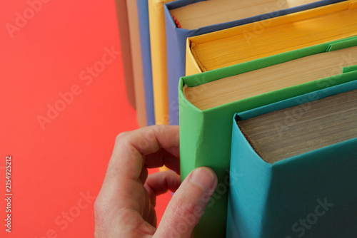 Books with colorful paper covers are lined up against colorful paper backgrounds. School education featuring attractive, bright, and colorful books.