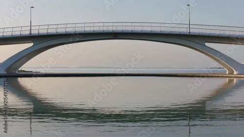 Modern arch bridge reflecting in the calm water