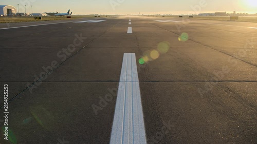 First-person view moving down an empty airport runway at sunrise