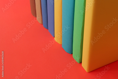Books with colorful paper covers are lined up against colorful paper backgrounds. School education featuring attractive, bright, and colorful books.