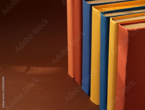 Books with colorful paper covers are lined up against colorful paper backgrounds. School education featuring attractive, bright, and colorful books.