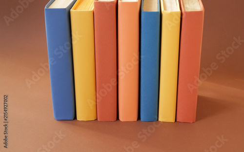 Books with colorful paper covers are lined up against colorful paper backgrounds. School education featuring attractive, bright, and colorful books.