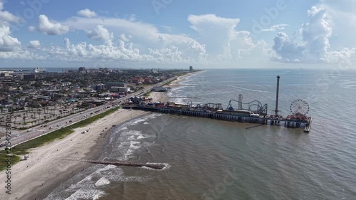 Aerial view of Galveston Island coastal town in Texas and Historic Pleasure Pier amusement park on ocean shoreline on a Sunny Day
