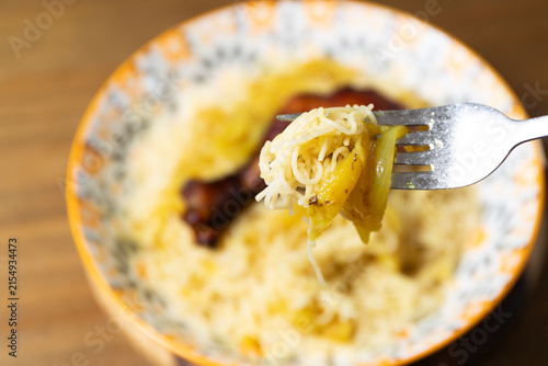 Macro close-up of a fork holding a bite of Moroccan Seffa vermicelli with onion sauce