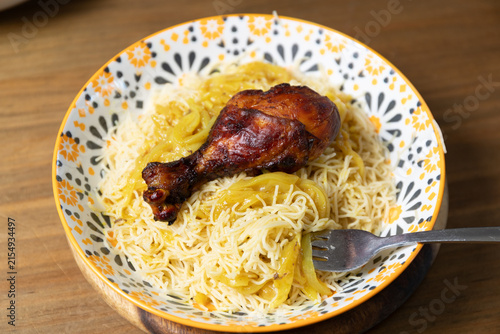 Top down view of traditional Moroccan Seffa Medfouna with roasted chicken and onion sauce