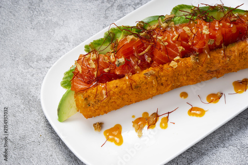 Corn dog sushi with tuna, cucumber, and sauce on a plate.