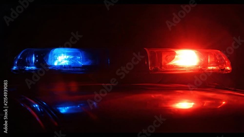 Red and blue flashing LED emergency lights on the roof of a police car at night