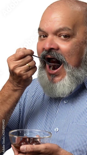 An Indian Asian elderly businessman with a beard is secretly enjoying a bowl of delicious gulabjamun