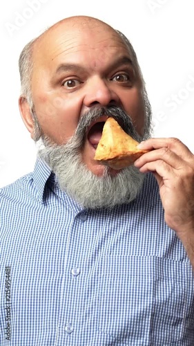 Indian Asian elderly gentleman with a beard  enjoys a samosa secretely ,showing love for Indian snacks