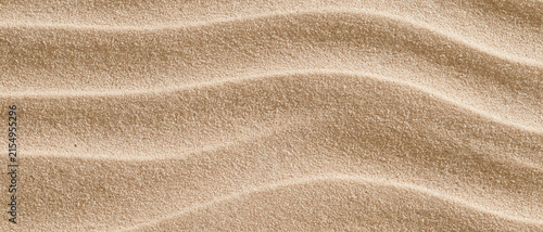 Rippled beach sand texture in beige and light brown tones, natural coastal backdrop with copy space