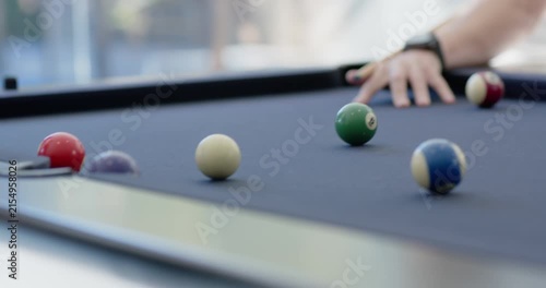 Player drawing back cue, striking cue ball, sending balls toward left pocket on table to score