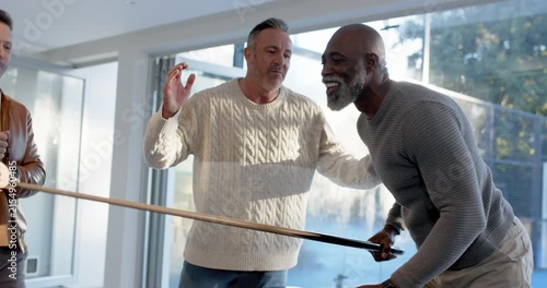 Diverse men at pool table playing with cues, cheering African American man lining-up, taking shot