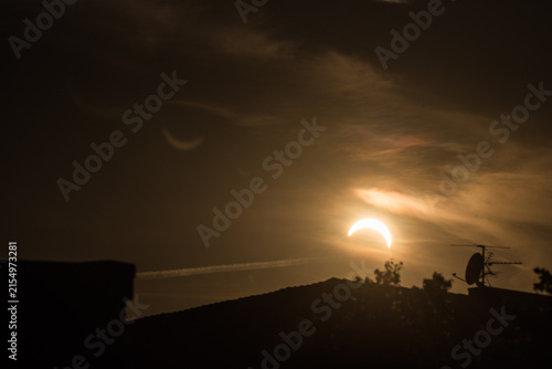 Partial solar eclipse forming a glowing sun crescent over city rooftop silhouettes at night in Kiel Germany Baltic Sea 2026 
