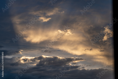Photography Golden sunbeams penetrating heavy storm clouds during late afternoon with dark side framing