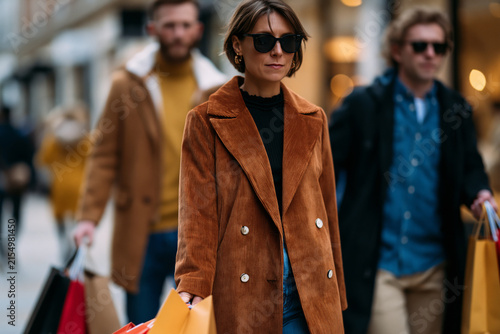 Stylish shoppers carrying purchases during a seasonal sale, natural daylight, urban shopping destination, premium lifestyle branding visual, captured with exceptional clarity and vibrant colors