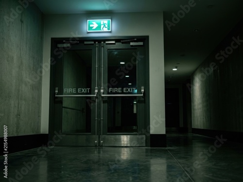 Emergency Exit Sign Illuminated In A Dark Hallway Showing Safety And Way Out