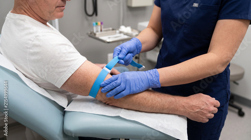 Medical professional applying tourniquet to arm for blood draw  