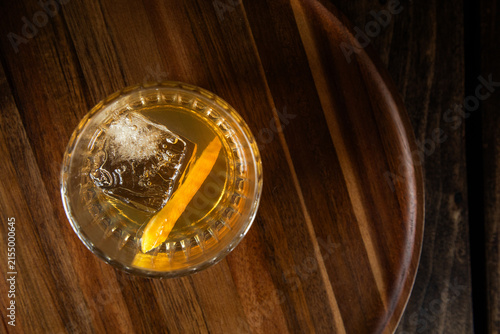 Close up of a classic old fashioned cocktail on a dark wooden background garnished with an orange twist.