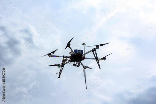 Hexacopter drone with six rotors flying against cloudy sky. Modern unmanned aerial vehicle with multiple propellers in mid-air. Technology and aviation concept