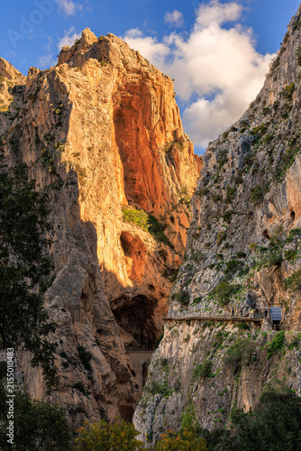 Vast Garganta del Chorro canyon with sunlit peak and tiny walkway