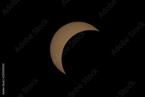 partial solar eclipse over dark yellow sky at night, mysterious and scientific astronomical view of sun and moon in blackness, serene and dramatic natural phenomenon, educational resource.