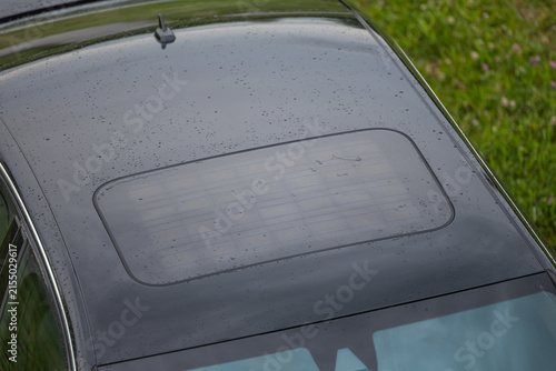 Black Car Roof With Solar Panels And Rain Drops On Closed Sunroof Glass Panel Over Windshield