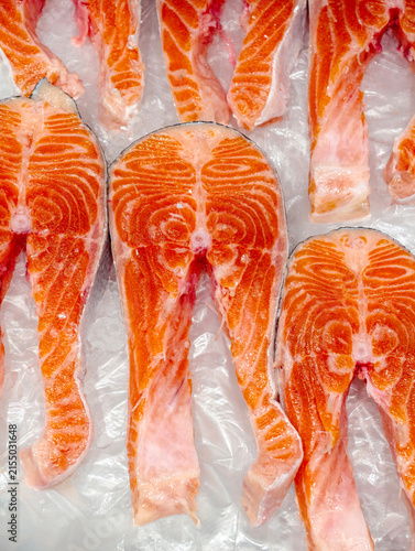 Fresh trout fillets displayed on a plastic sheet over ice at a supermarket seafood counter, highlighting chilled red fish ready for customer selection