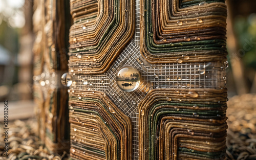 Close-up of layered brown and green fabric strips with glass spheres and water droplets