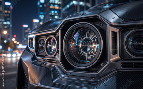 Close-up of a dark metallic car headlight assembly with complex lens optics at night