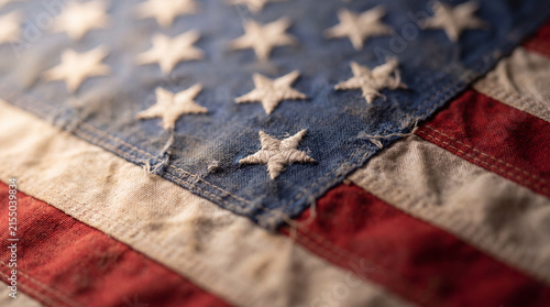 A detailed, shallow depth of field shot of an antique United States flag, showing texture and wear on its stars and stripes.