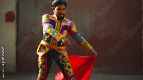 Matador in vibrant embroidered traje de luces performing dramatic cape pass with charging bull