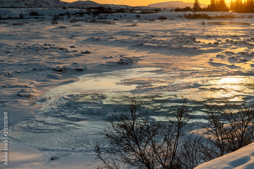 A scenic outdoor landscape shot from the Thingvellir National Park in Iceland on a beautiful sunny winter afternoon. This snowcovered landscape marks the continental divide between America and Europe.