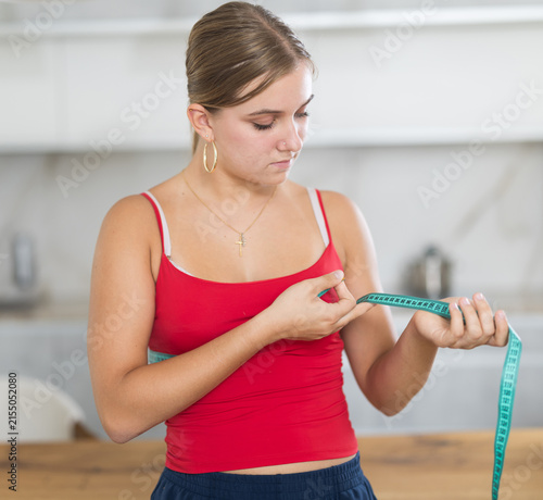Girl monitors slimness of body and measures circumference of waist or hips using centimeter, diet, maintaining harmony and balance, food discipline, and healthy lifestyle.