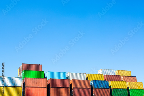 Colorful shipping containers stacked at a cargo terminal under a clear blue sky, representing global logistics, freight transportation, supply chain, import and export, and international commerce.