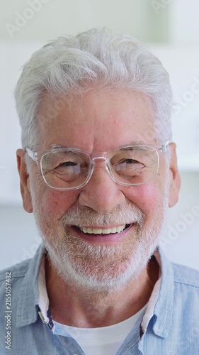 Portrait of a happy senior man with grey hair and a beard, wearing eyeglasses and smiling warmly, showing a positive and cheerful expression while looking directly at the camera
