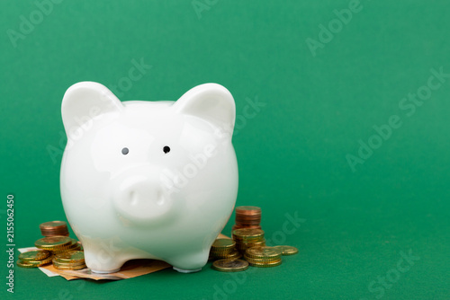 Piggy bank with coins on color background