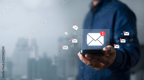 Person holds smartphone, receives email notifications, symbolizing digital communication, mobile connectivity, and information flow in an interconnected world