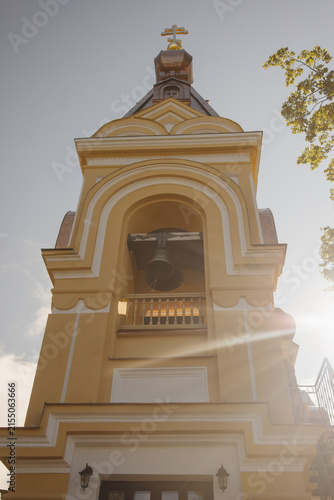 Bild auf Leinwand Orthodox church bell tower with cross and visible bells illuminated by bright su