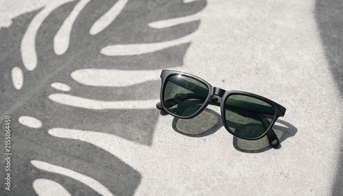 Stylish sunglasses with shadows on a light surface